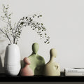 Decorative vases and a white vase with branches on a shelf against a light gray wall.